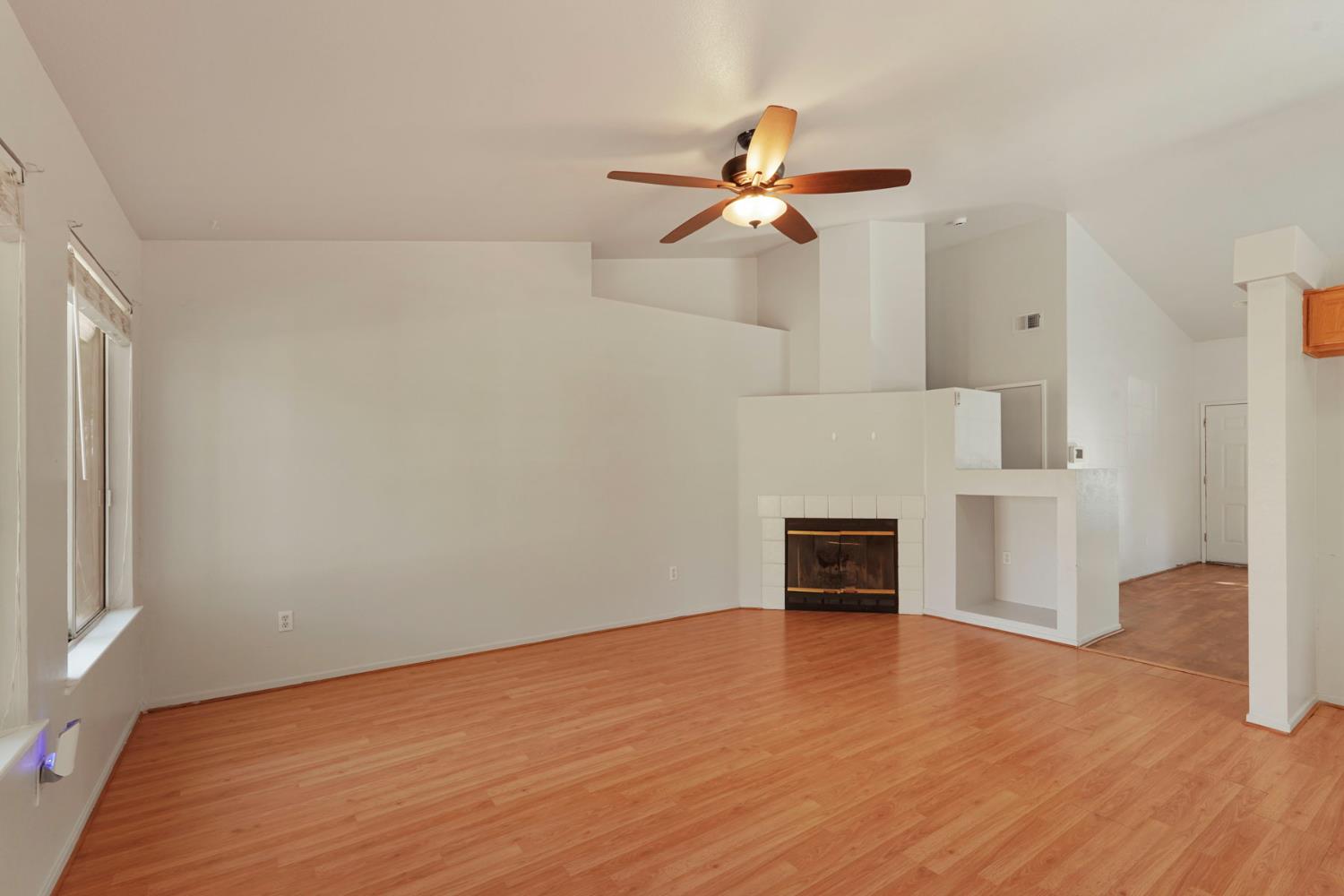 2449 Calvert Street Stockton, CA 95210 - Photo 16 of 37 an empty room with wooden floor a ceiling fan and windows