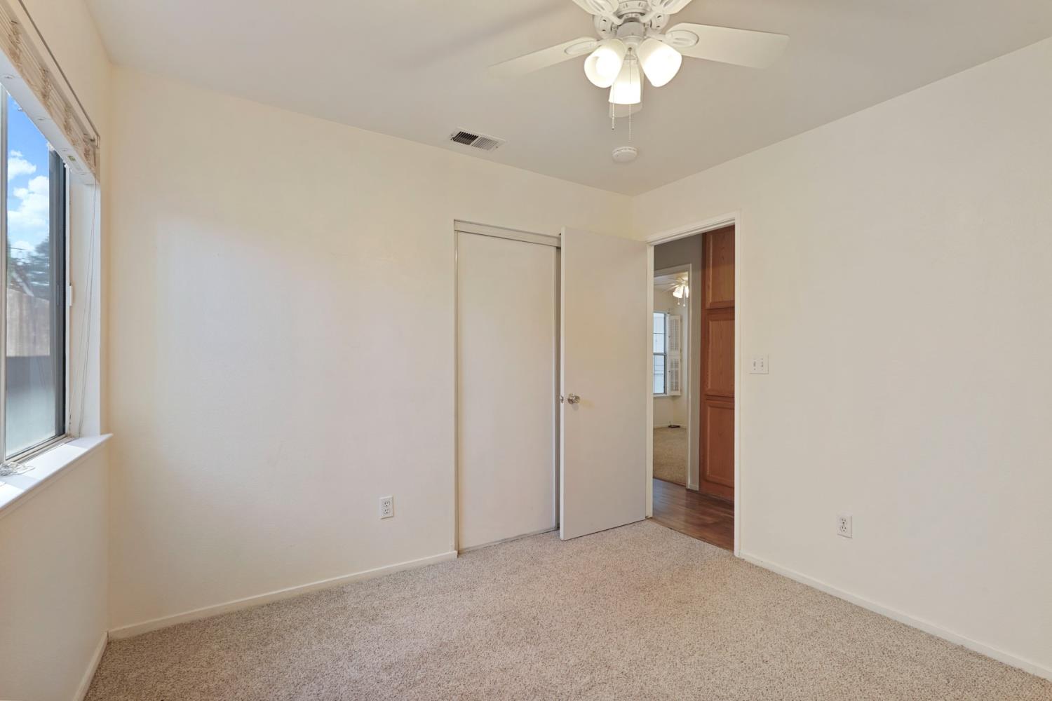 2449 Calvert Street Stockton, CA 95210 - Photo 21 of 37 an empty room with a chandelier fan and windows