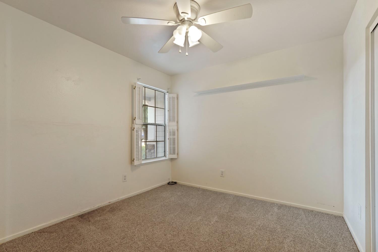 2449 Calvert Street Stockton, CA 95210 - Photo 22 of 37 an empty room with a chandelier fan and windows