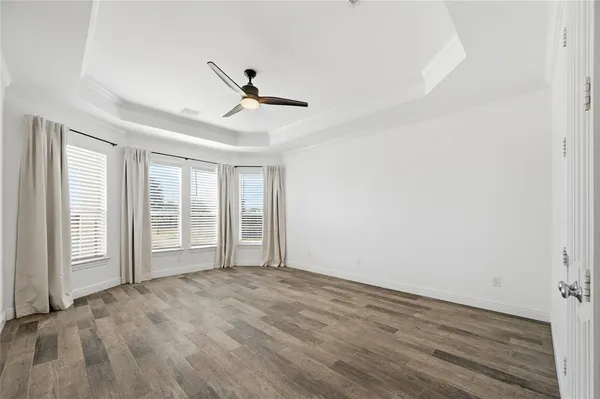 an empty room with windows and ceiling fan