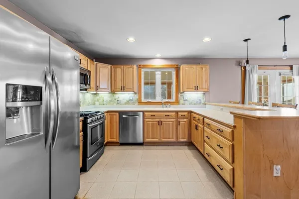 a kitchen with stainless steel appliances granite countertop a refrigerator a sink a stove and oven