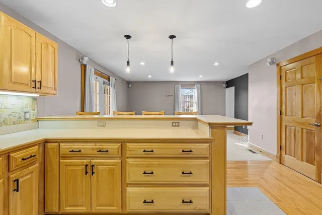 a view of room with kitchen island stainless steel appliances wooden floor and window