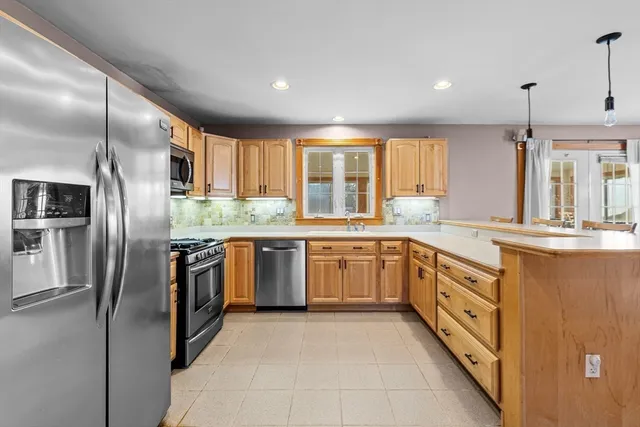 a kitchen with stainless steel appliances granite countertop a refrigerator a sink a stove and oven