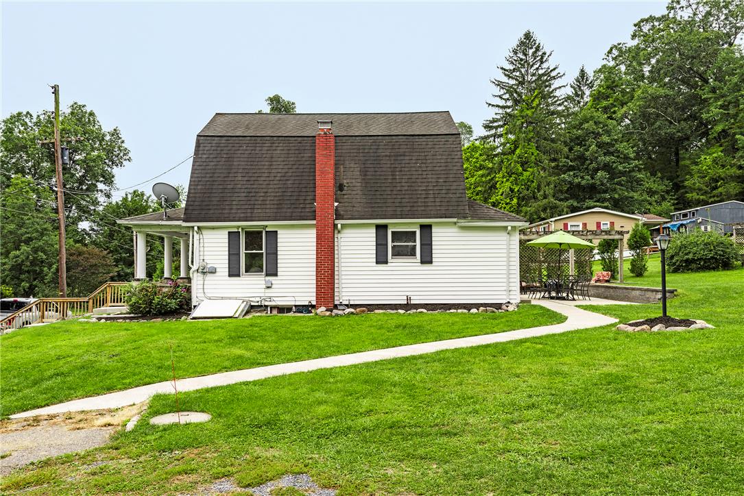280 Oak Road Bangor, PA 18013 - Photo 37 of 52 Lush green lawns and concrete walkways surround this classic white home with a brick chimney.
