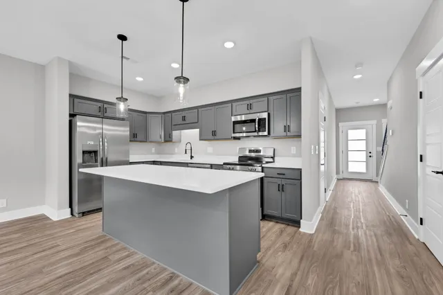 a large kitchen with stainless steel appliances kitchen island a large counter top and a wooden floors