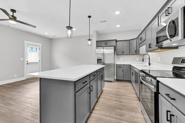 a kitchen with stainless steel appliances granite countertop a sink a stove and a wooden floors