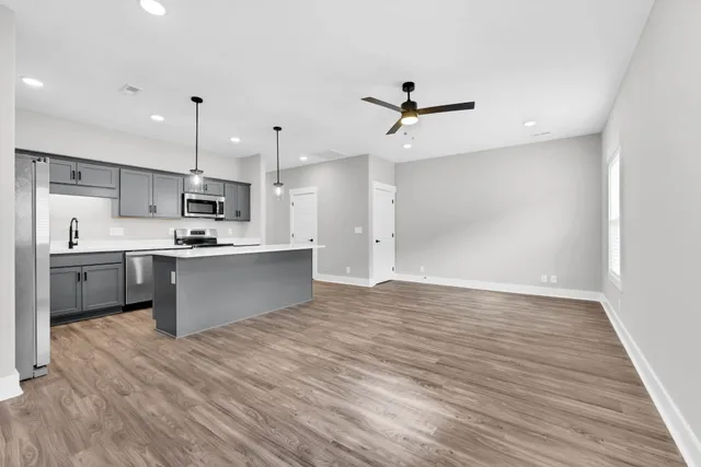 a large kitchen with stainless steel appliances kitchen island a sink dishwasher a refrigerator and a oven with wooden floor