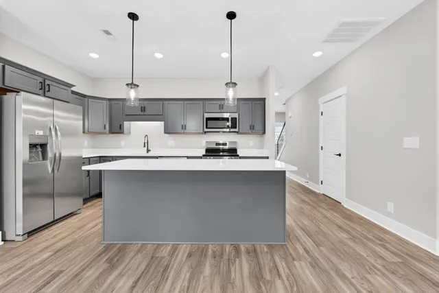 a kitchen with stainless steel appliances granite countertop a sink a stove a refrigerator and island with wooden floor