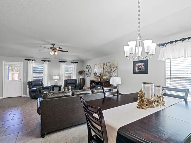 a living room with furniture a rug kitchen view and a window