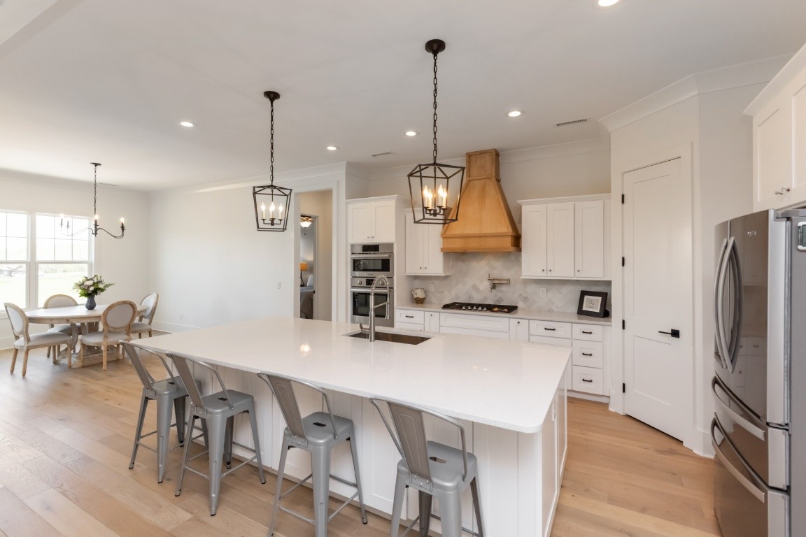 6926 Cairo Bend Road Lebanon, TN 37087 - Photo 11 of 42 a kitchen with stainless steel appliances granite countertop a sink a stove a refrigerator a center island a dining table and chairs
