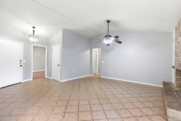 a view of an empty room with chandelier fan