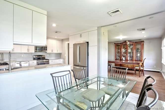 60 Brewer Road Monsey, NY 10952 - Photo 10 of 32 a kitchen with stainless steel appliances granite countertop a stove a refrigerator a kitchen island a table and chairs
