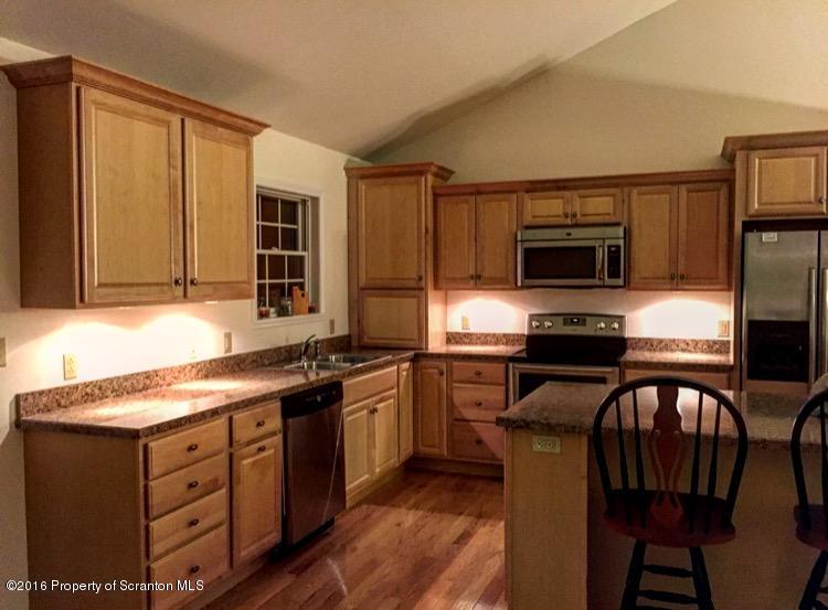 106 Rails Road Tunkhannock, PA 18657 - Photo 8 of 31 a kitchen with stainless steel appliances granite countertop a stove top oven a sink dishwasher a dining table and chairs with wooden floor