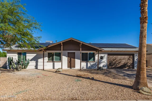 a view of a house with a yard and large tree