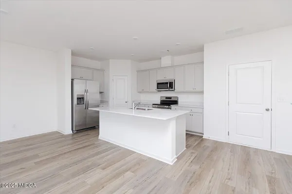 a kitchen with stainless steel appliances a white stove top oven cabinets and a wooden floor