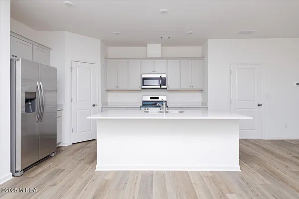 a kitchen with stainless steel appliances a sink a refrigerator and wooden floor