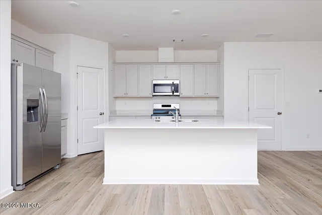 a kitchen with stainless steel appliances a sink a refrigerator and wooden floor