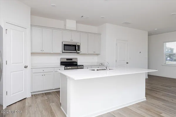 a kitchen with stainless steel appliances a sink a stove a microwave and cabinets