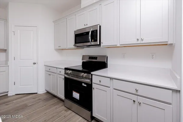 a kitchen with white cabinets and black appliances