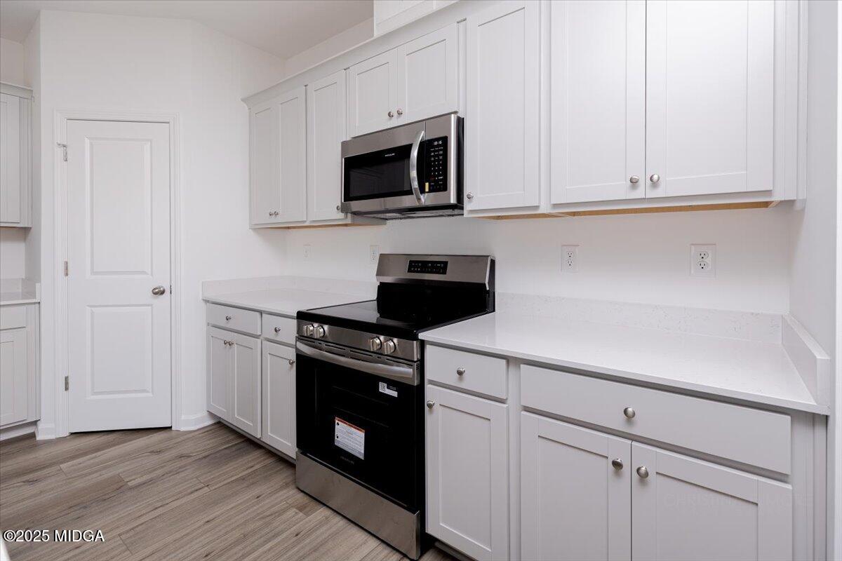 218 Hickory Rdg Trail Kathleen, GA 31047 - Photo 23 of 48 a kitchen with white cabinets and black appliances
