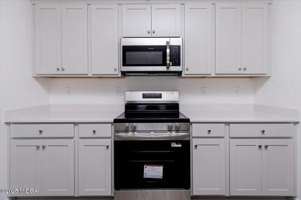 a kitchen with white cabinets and stainless steel appliances