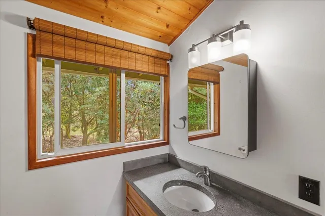 a bathroom with a granite countertop sink a toilet and a window