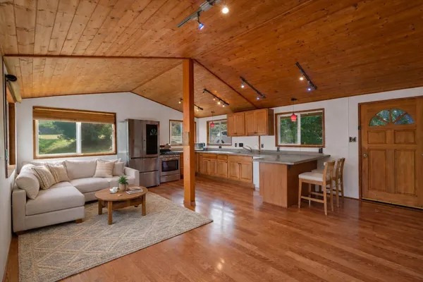 a living room with furniture and kitchen view with wooden floor