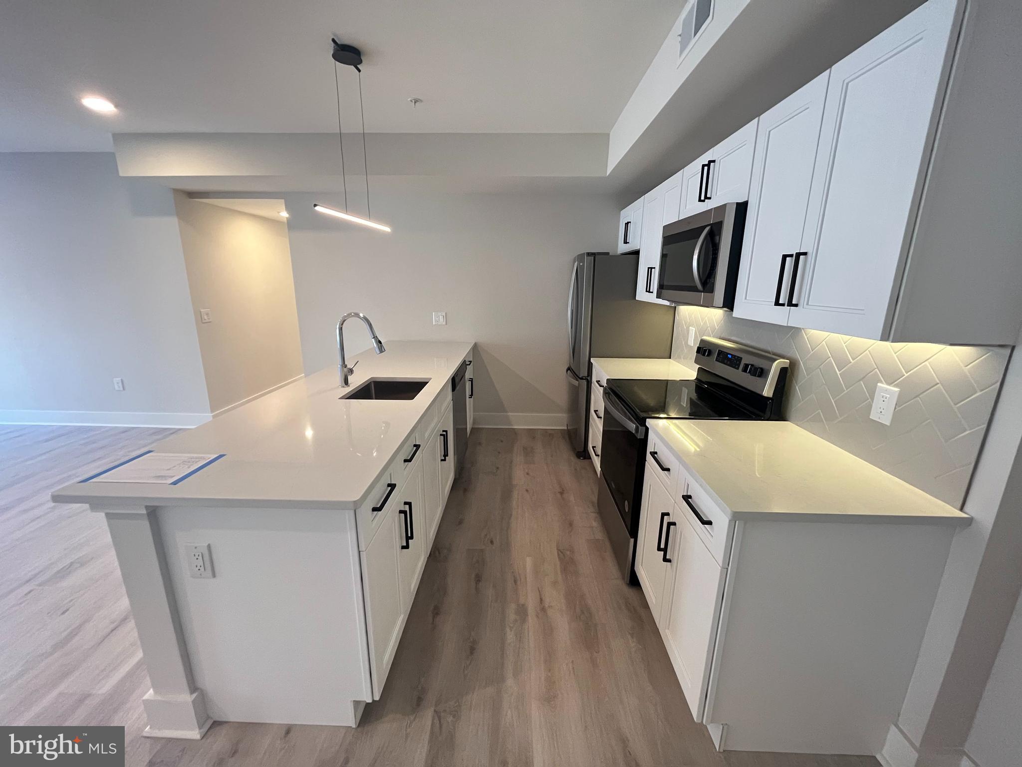 1805 North Howard Street, Unit 303 Philadelphia, PA 19122 - Photo 5 of 25 a kitchen with stainless steel appliances a sink a stove top oven a counter space and cabinets