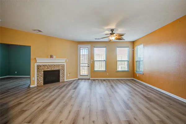 wooden floor fireplace and windows in an empty room