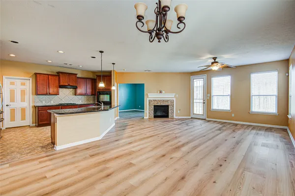 a view of an empty room with a kitchen and fireplace