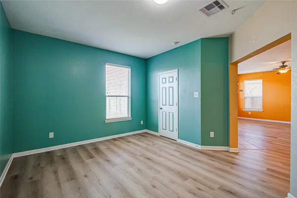 an empty room with wooden floor and windows