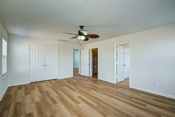 a view of empty room with wooden floor and ceiling fan
