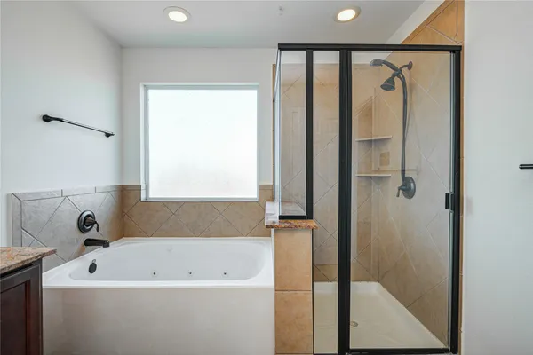 a bathroom with a bathtub a shower and a window