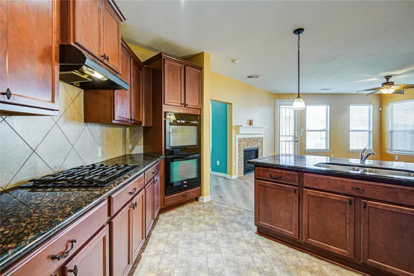 a kitchen with kitchen island granite countertop a sink a counter space appliances and cabinets