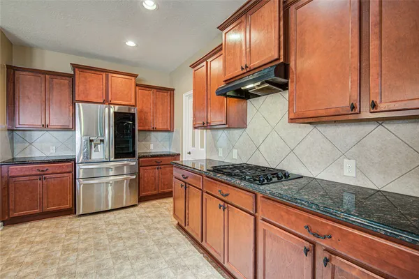 a kitchen with stainless steel appliances granite countertop a stove a sink dishwasher and refrigerator with wooden cabinets