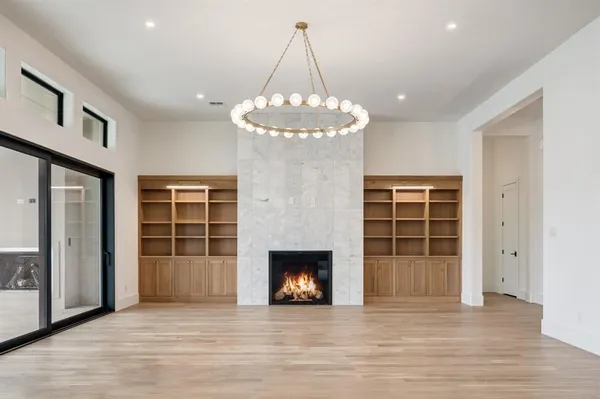 an empty room with wooden floor fireplace and windows