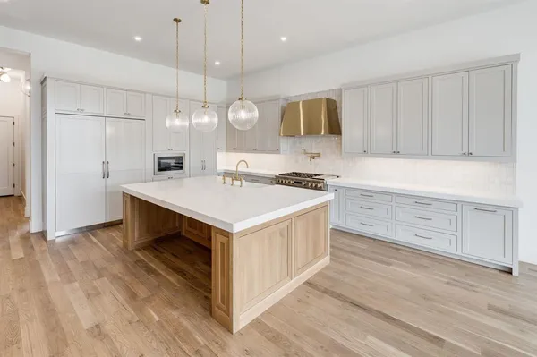 a kitchen that has a lot of cabinets in it and wooden floors