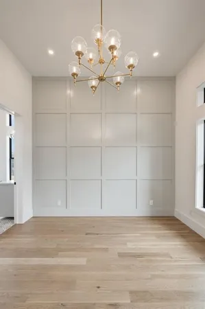 a view of a room with a chandelier fan and wooden floor