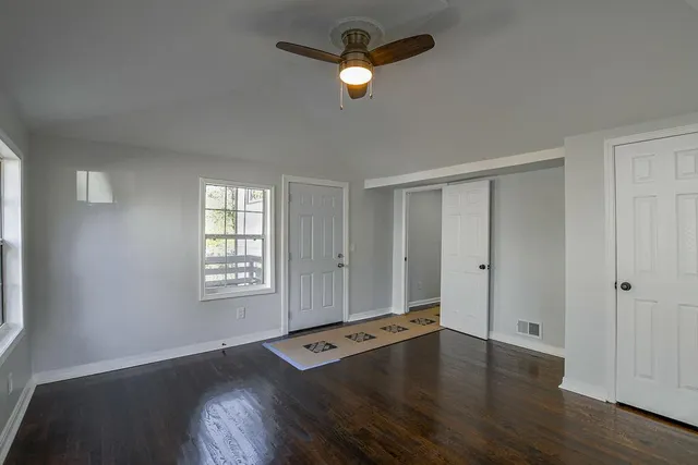 a view of empty room with wooden floor and fan