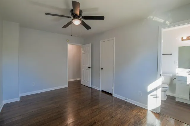a view of an empty room with wooden floor and a ceiling fan