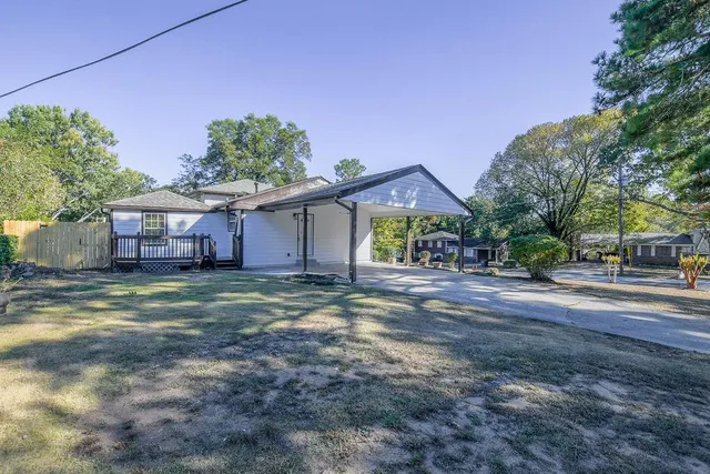 a view of a house with a yard and large tree