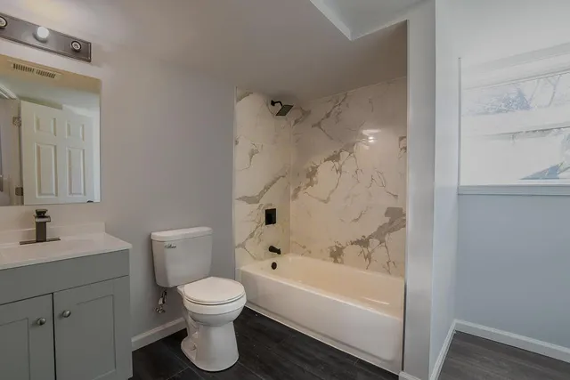 a bathroom with a toilet sink vanity tub and shower