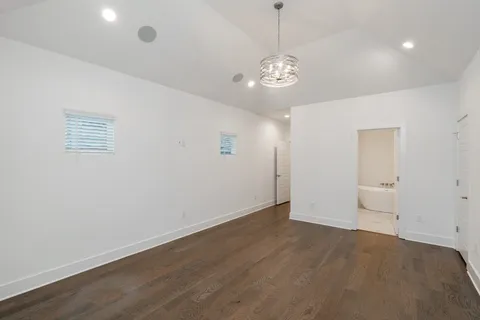 an empty room with wooden floor and chandelier
