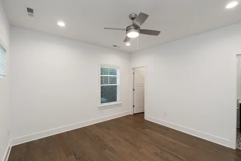 an empty room with wooden floor chandelier fan and windows