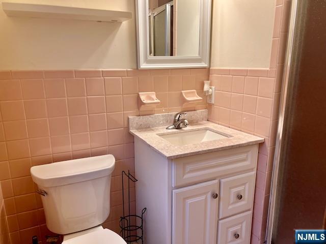 225 6th Street, Unit 2 Fairview, NJ 07022 - Photo 10 of 14 a bathroom with a sink a toilet and a mirror