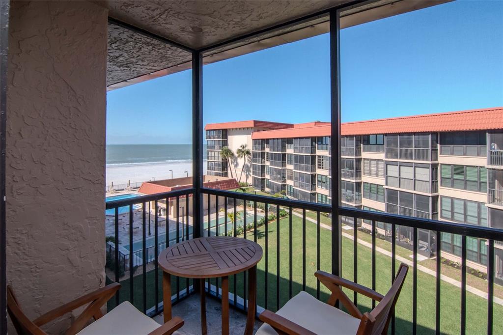 17580 Gulf Boulevard, Unit 403 Redington Shores, FL 33708 - Photo 19 of 27 a view of a balcony with a table and chairs with wooden floor