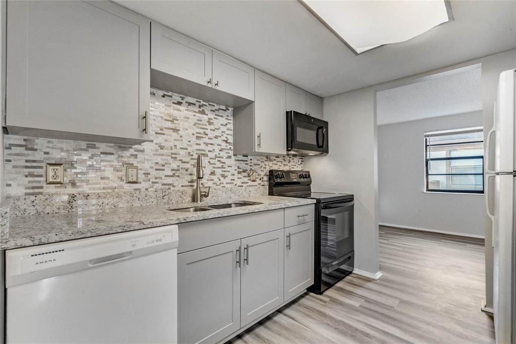 4907 Lake Ridge Road, Unit H Orlando, FL 32808 - Photo 6 of 14 a kitchen with stainless steel appliances white cabinets and a wooden floor