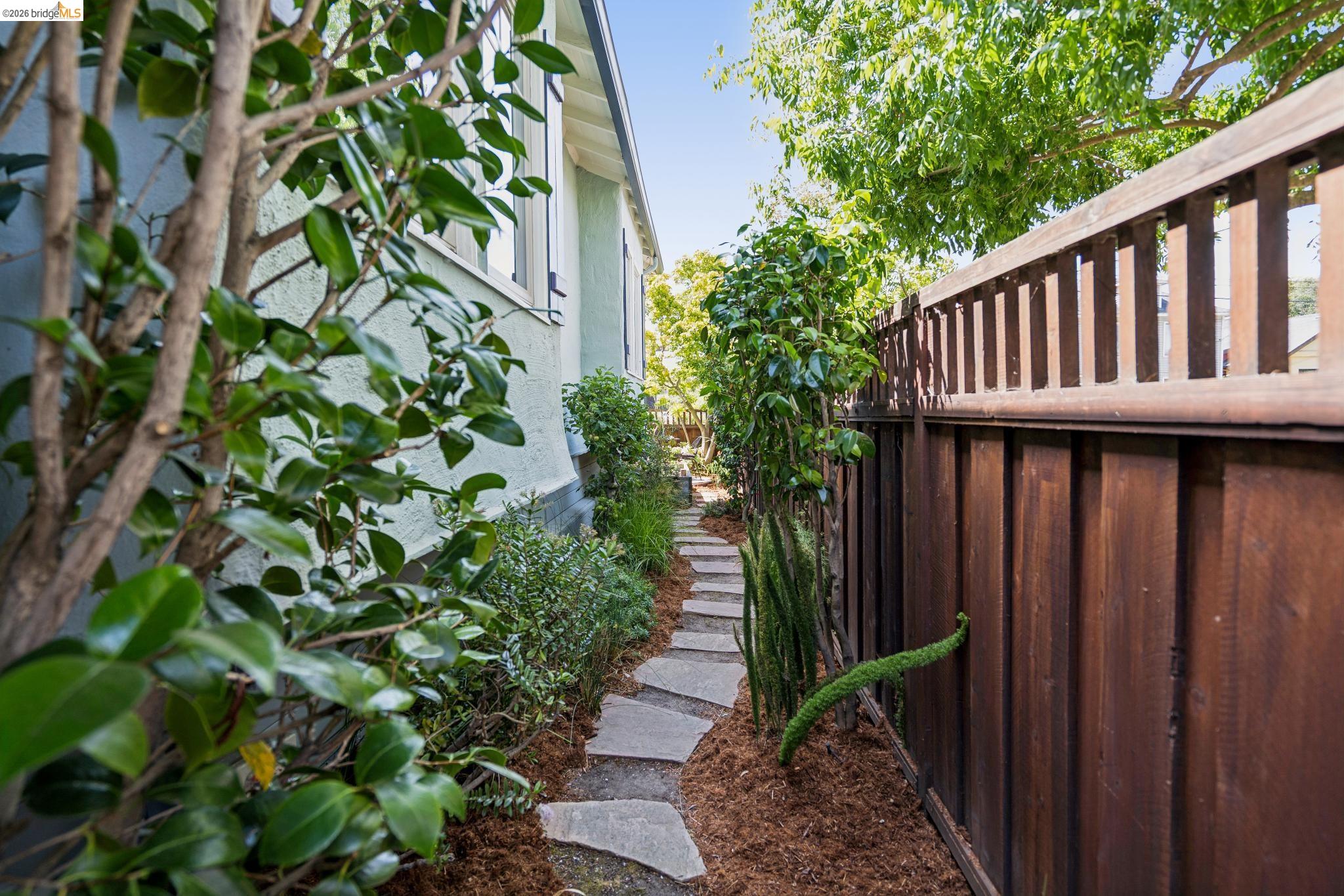1701 Derby Street Berkeley, CA 94703 - Photo 39 of 39 Stone paver pathway bordered by lush greenery and a wood privacy fence