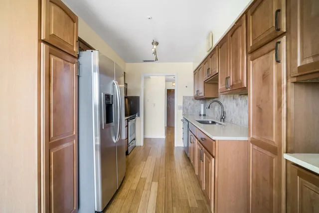 a kitchen with stainless steel appliances granite countertop a refrigerator a sink and a stove