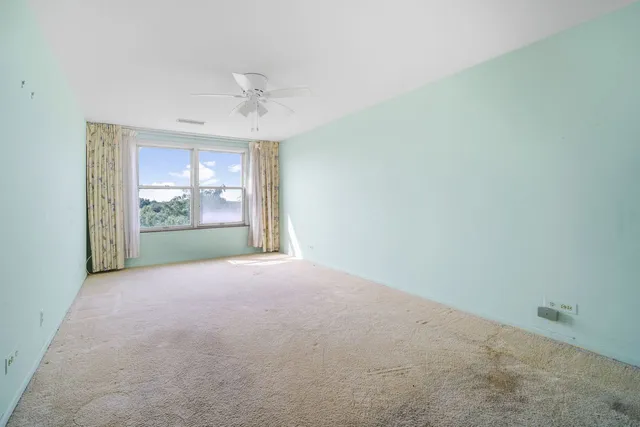 an empty room with windows and ceiling fan